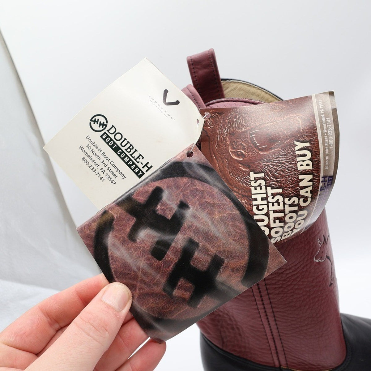Original Double-H Boot Company hangtags attached to burgundy cowboy boot