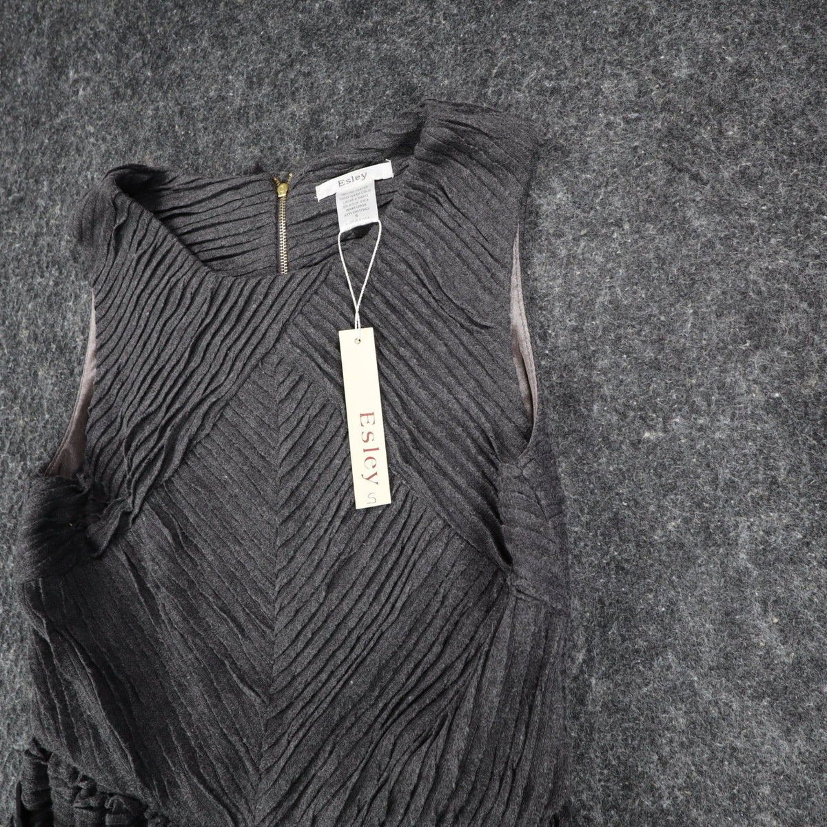 Angled close-up of the front of charcoal gray Esley sleeveless dress with textured pleats and a black belt