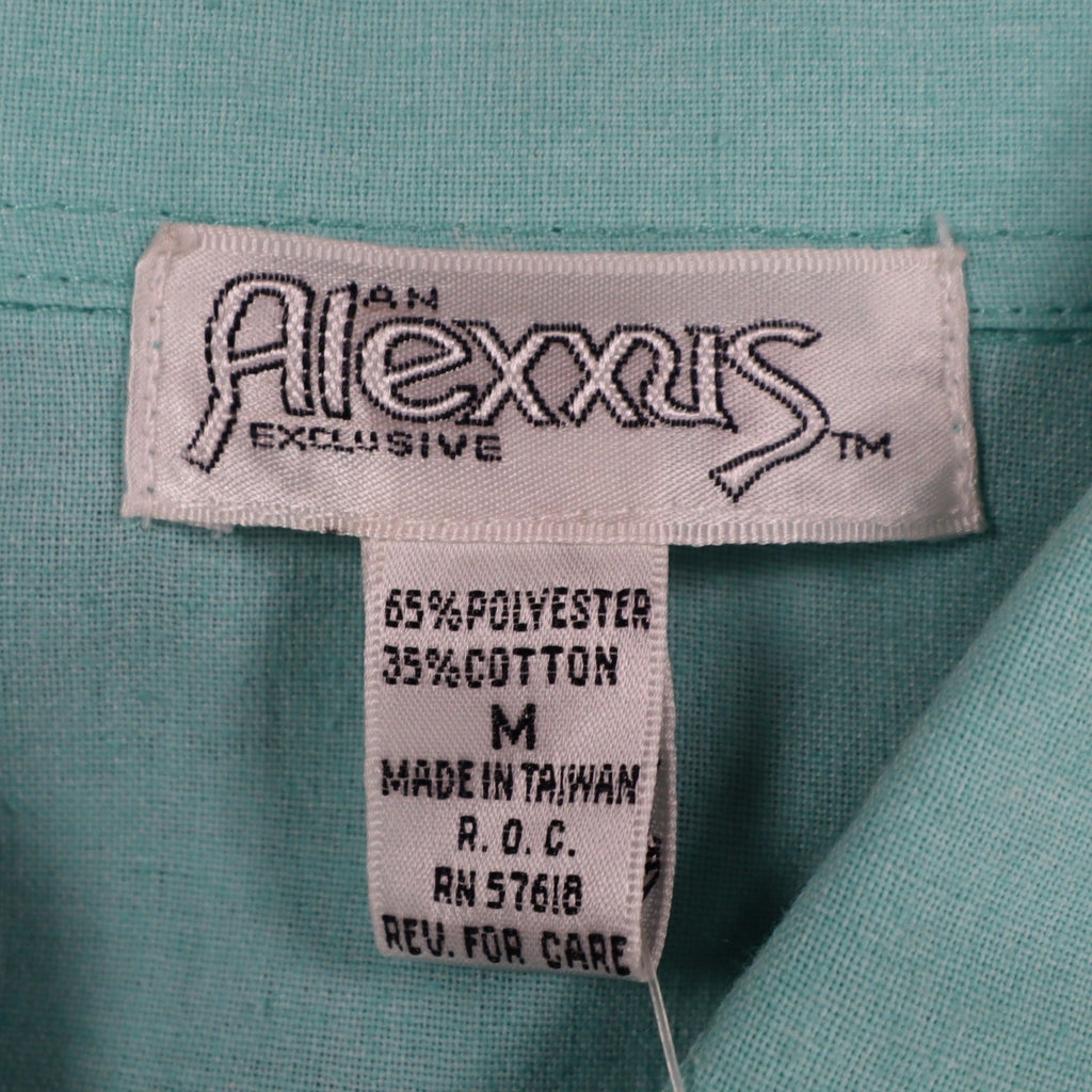 Close-up of the Alexxus brand, size and fabric-content labels inside an aqua blue shirt