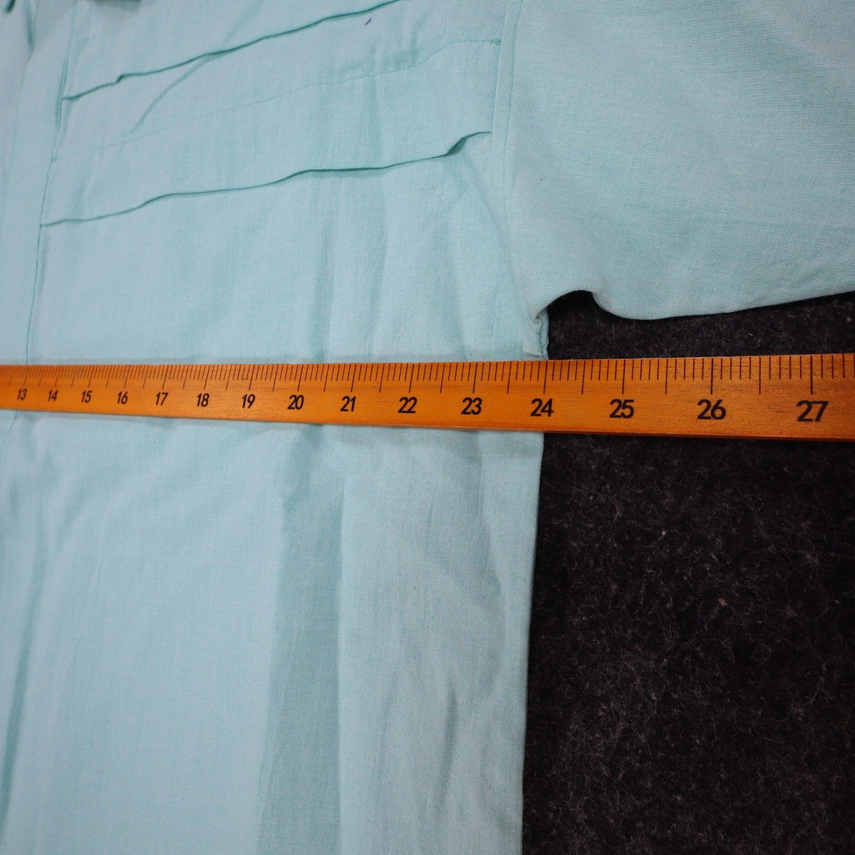 Ruler across the chest of aqua blue Alexxus short-sleeve shirt