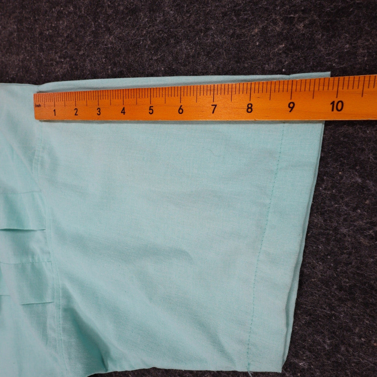 Ruler along the short sleeve of an aqua blue Alexxus short-sleeve shirt