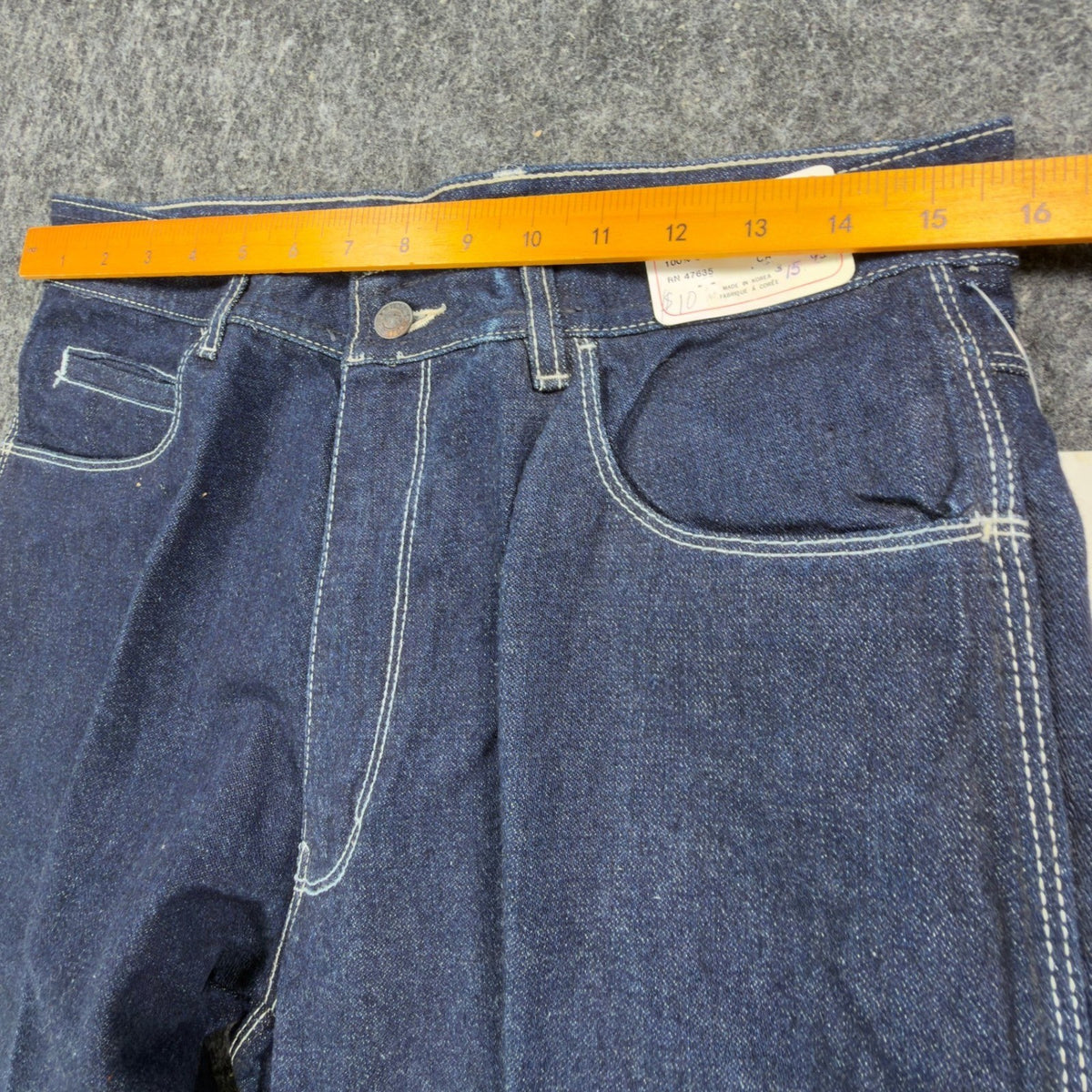 Ruler across the waistband of indigo Gino Cappeli bootcut jeans with white stitching