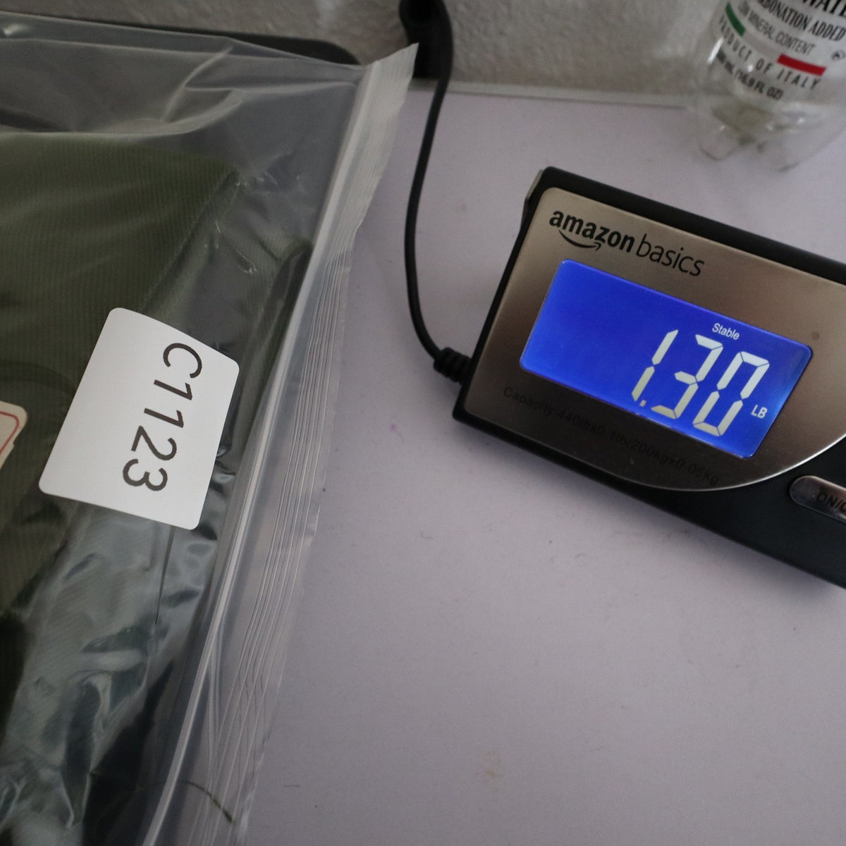 Green Aldens pants in an inventory-labeled clear bag beside a digital scale