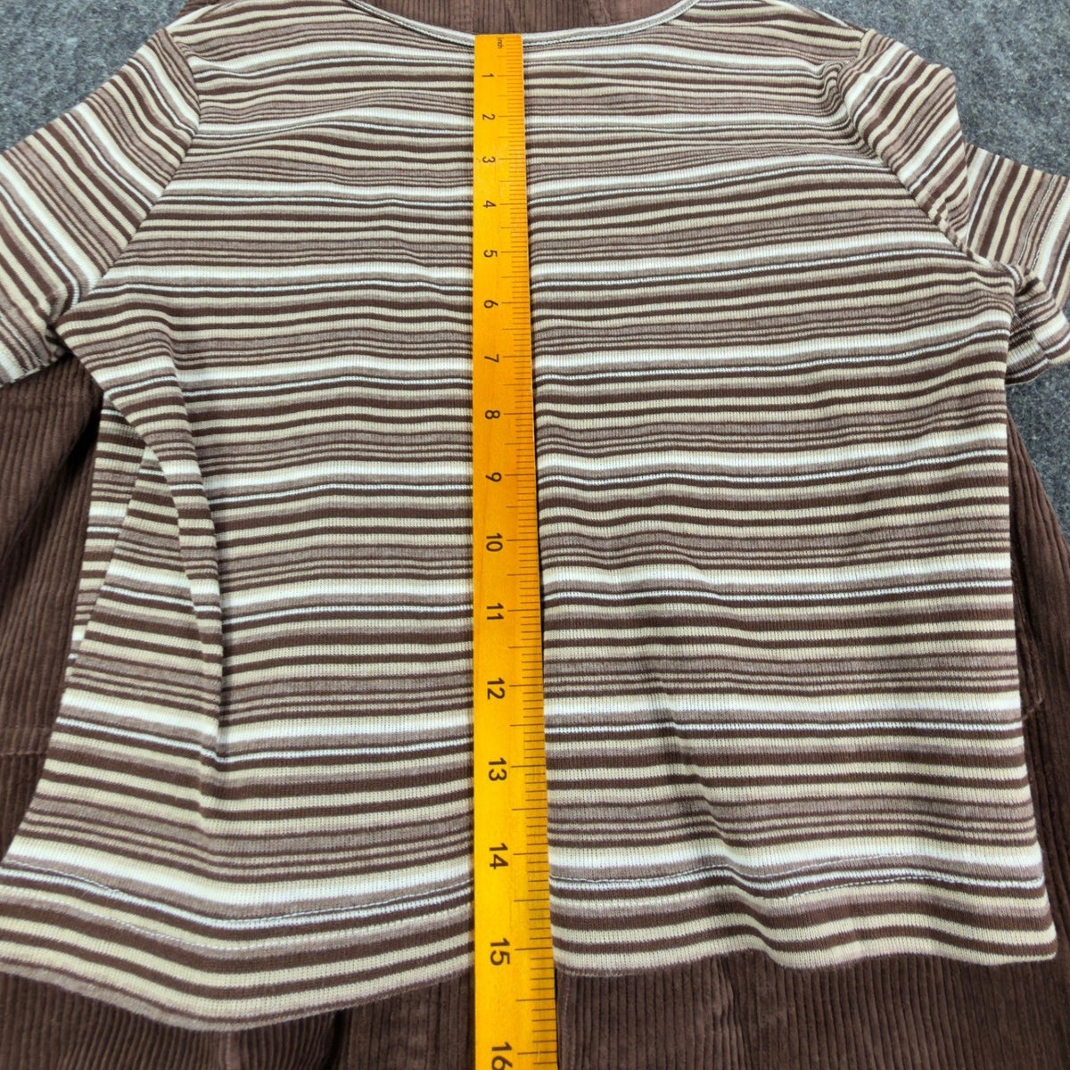 Ruler from the neckline to the hem of the striped Amy Too top laid over a brown jumper dress