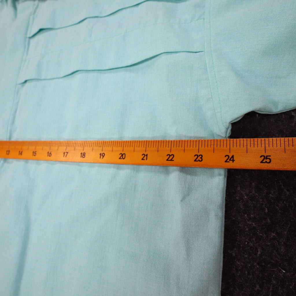 Ruler across the chest of aqua blue Alexxus short-sleeve shirt