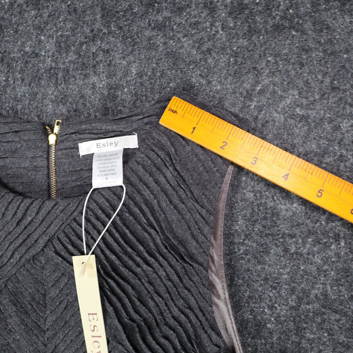 Ruler along the shoulder of charcoal gray Esley sleeveless dress with textured pleats and a black belt