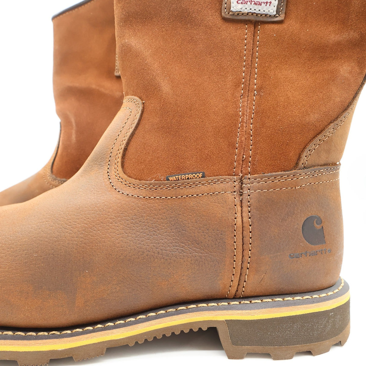 Brown Carhartt pull-on work boots, close-up of heel logo, stitching and Waterproof tab