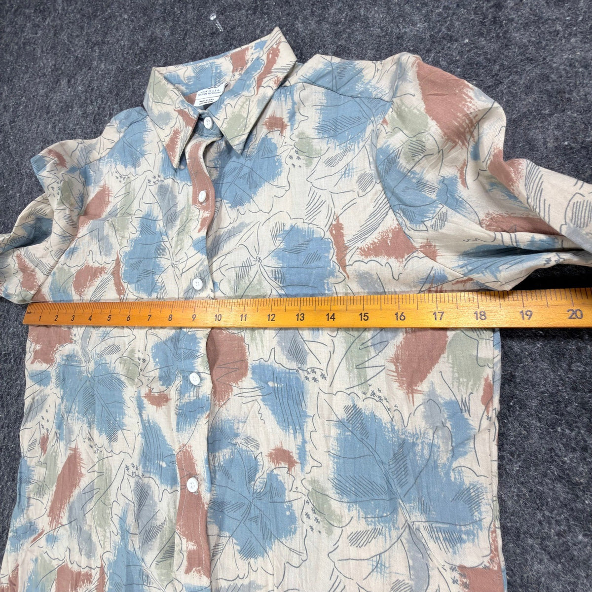 Cream Miss B long-sleeve shirt with blue, rust and green leaf print, ruler across chest