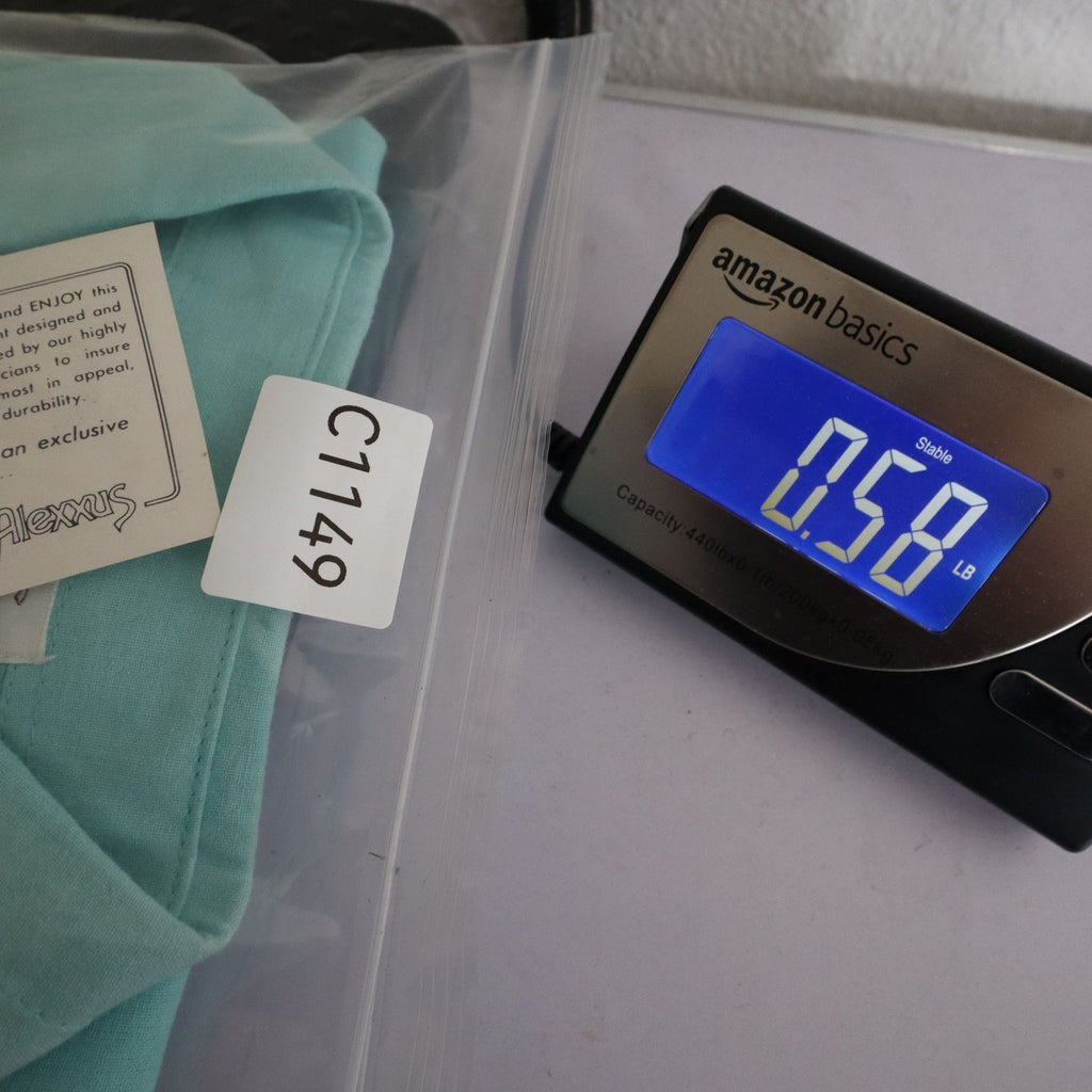 Aqua blue Alexxus short-sleeve shirt in an inventory-labeled clear bag beside a digital scale