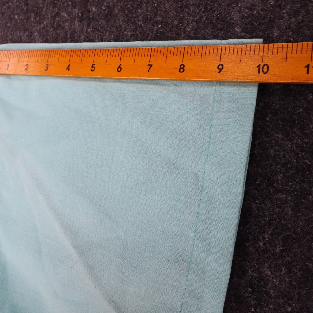 Ruler along the short sleeve of an aqua blue Alexxus short-sleeve shirt
