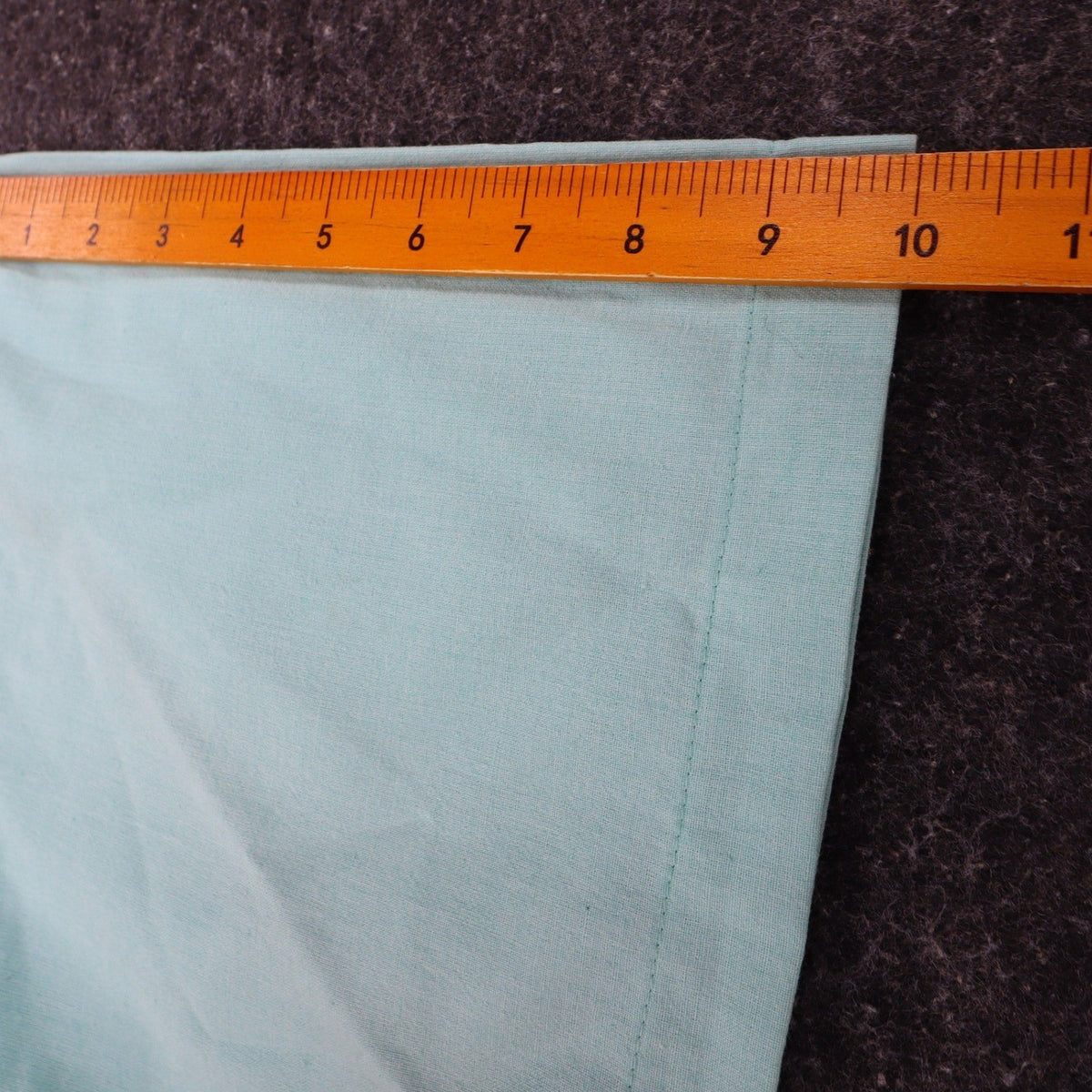 Ruler along the short sleeve of an aqua blue Alexxus short-sleeve shirt