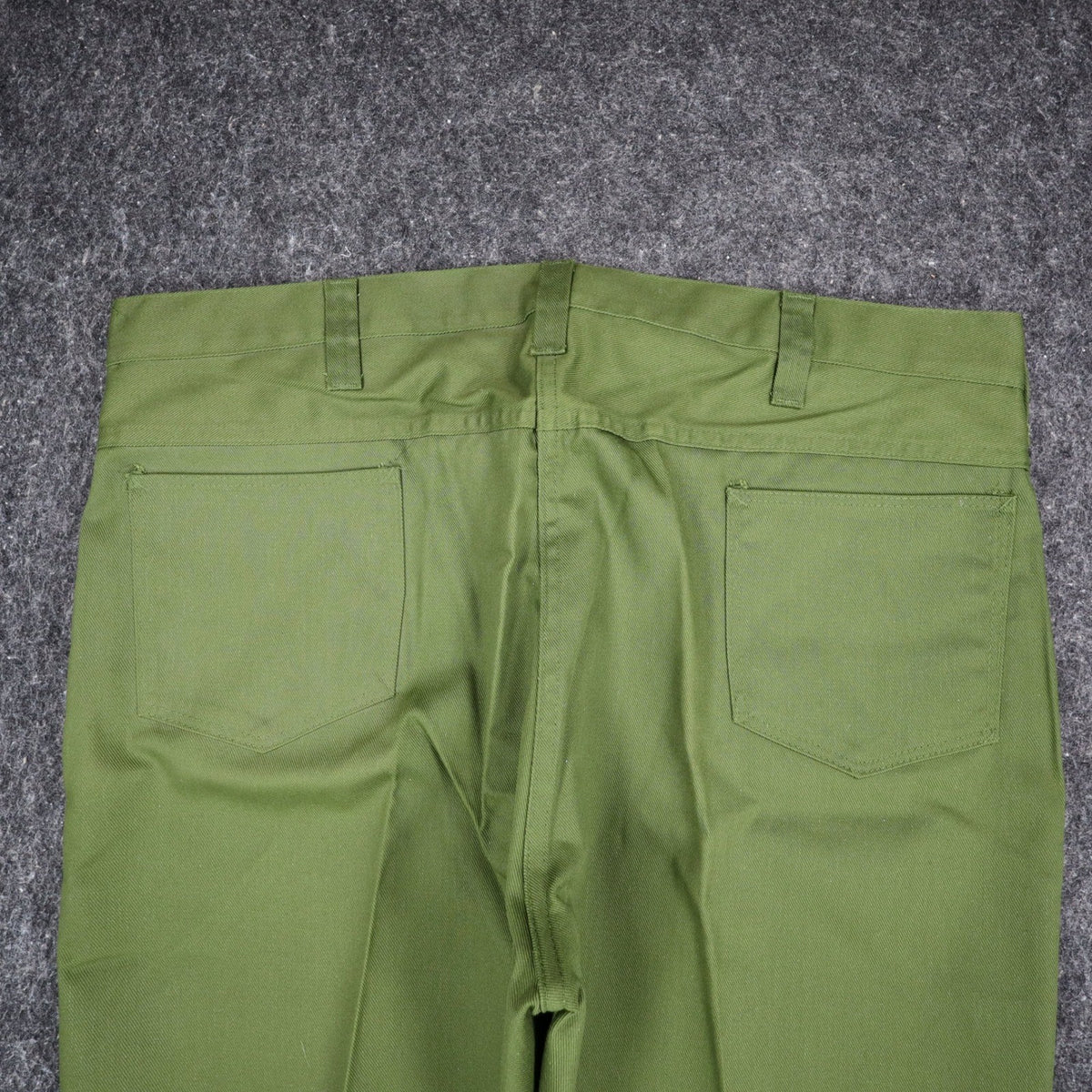 Close-up of the back waist and patch pockets of green Aldens pants