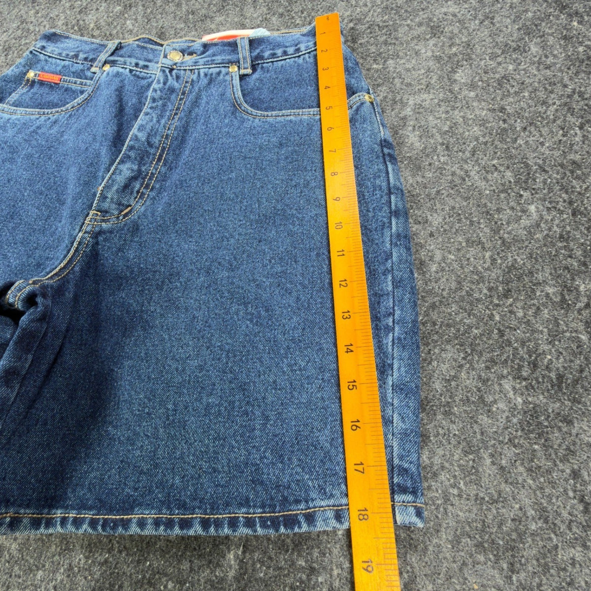 Ruler alongside the outer leg of blue Lawman denim shorts