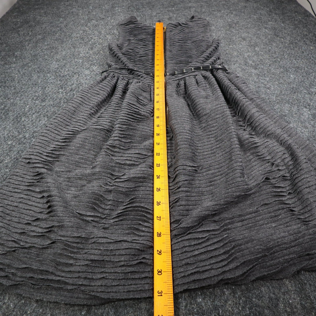 Ruler along the back length of charcoal gray Esley sleeveless dress with textured pleats and a black belt