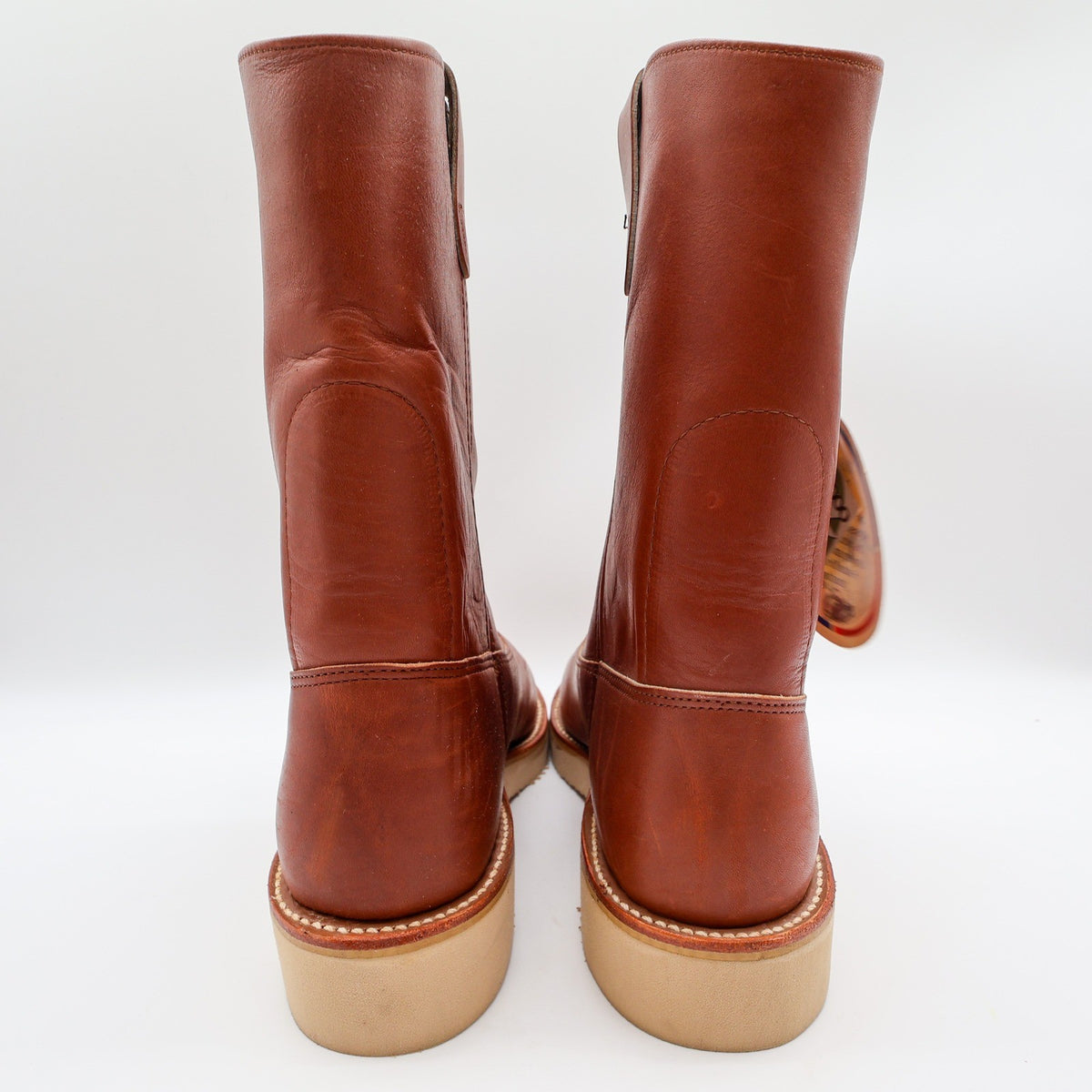Rear view of reddish-brown Double-H pull-on boots with cream wedge soles, showing heel seams and collars