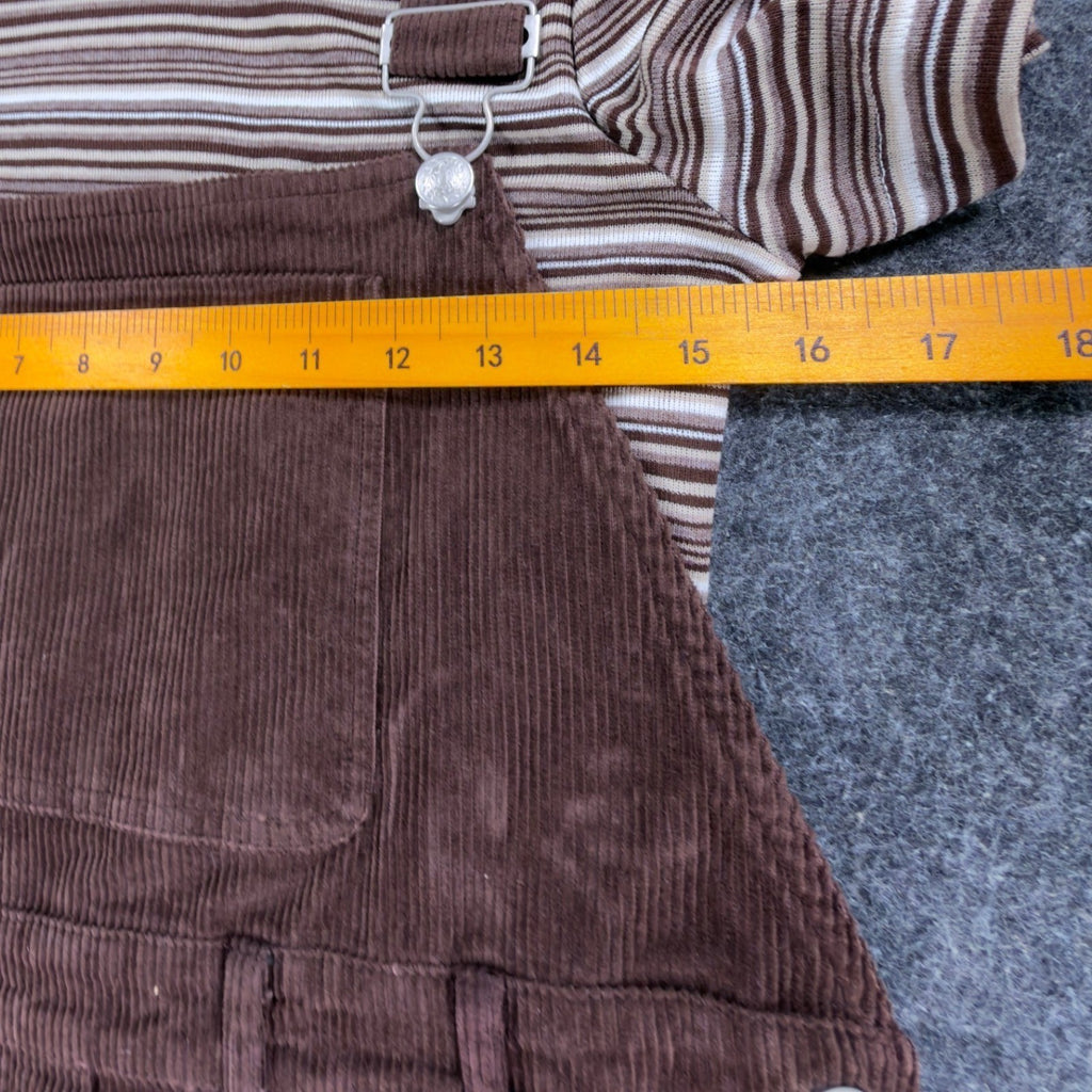 Ruler across the chest of a brown Amy Too jumper dress set, over the bib and striped top
