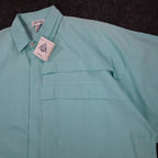 Angled close-up of the collar, front placket and chest pleats of an aqua blue Alexxus short-sleeve shirt