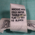 Close-up of the care-instruction label inside aqua blue Alexxus short-sleeve shirt
