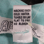 Close-up of the care-instruction label inside aqua blue Alexxus short-sleeve shirt