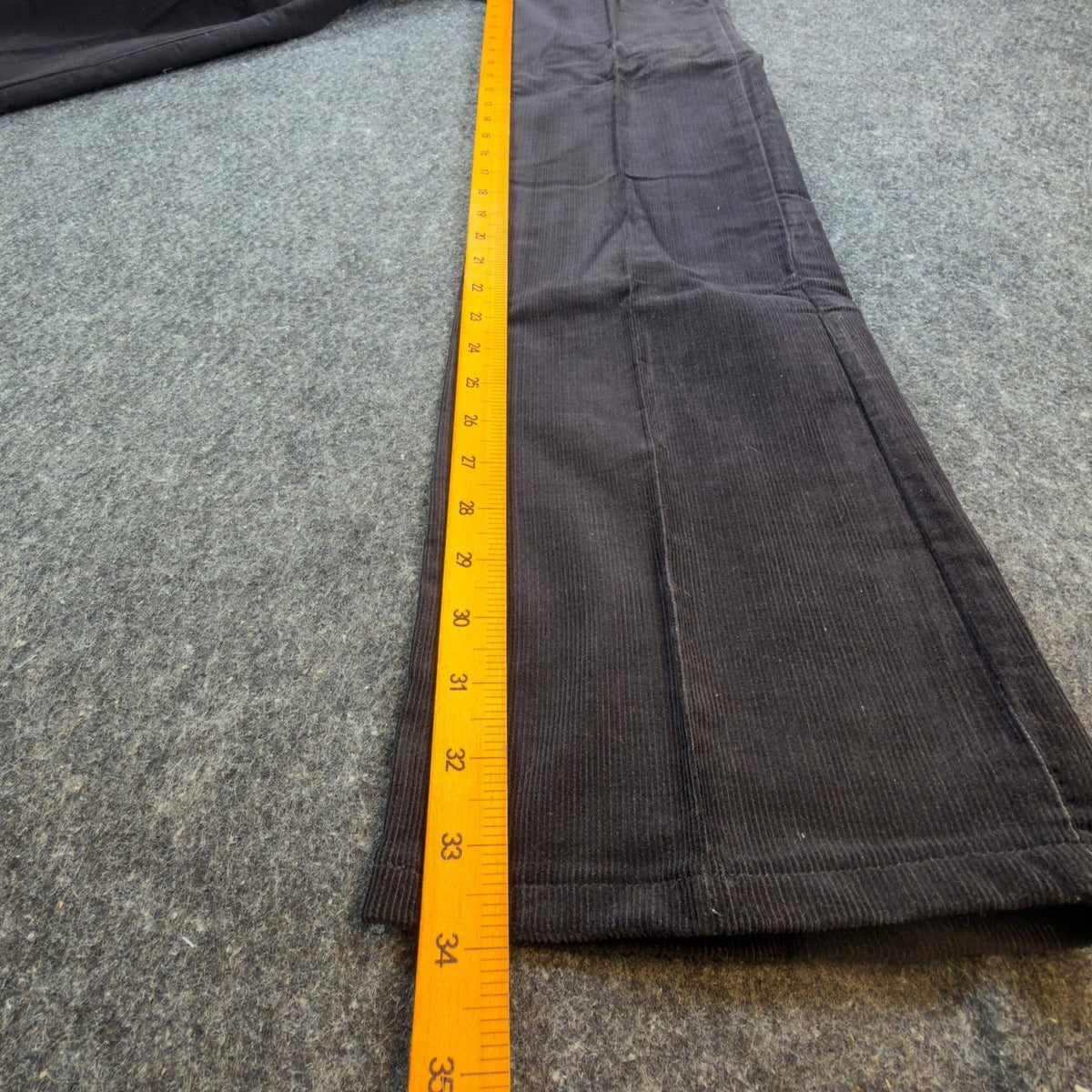 Black Maverick flared corduroy pants with embroidered back pockets, inseam ruler view